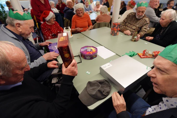 Individual prizes are being gifted to each attendee, so the people in the photo are looking at the item they've been given.