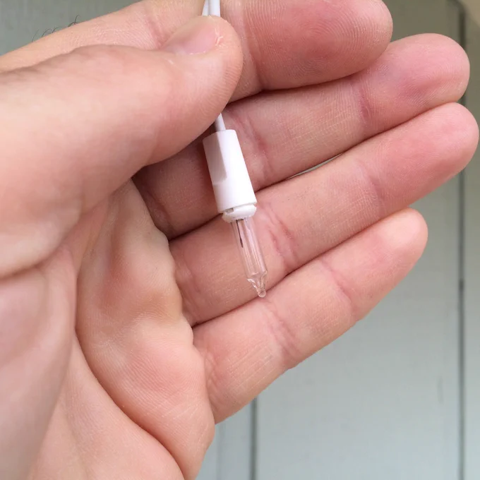 The same string light bulb fully inserted into a white socket, resting in the palm of a hand.

