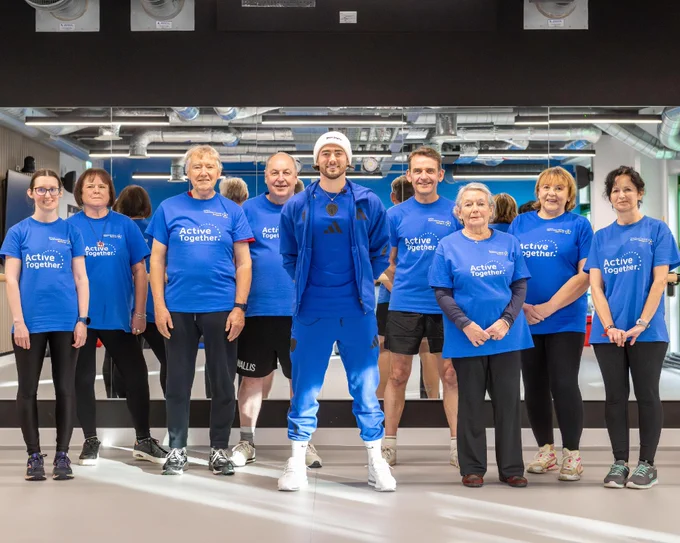 Jack Harrison stands alongside members of the Active Together service. They are in a gym environment and all smile at the camera.