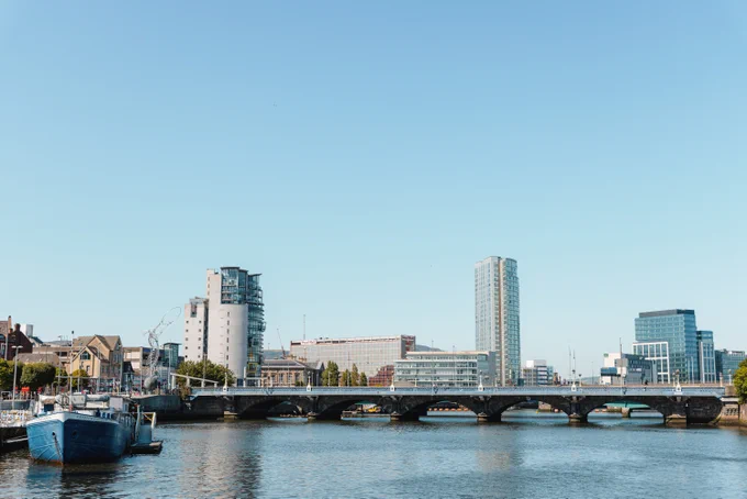 River Lagan with a bridge and tall buildings in the distance and a boat docked at the side.