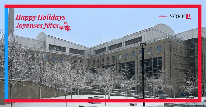 Season's greetings banner with 'Happy Holidays, Joyeuses fêtes' over a snowy scene at York University's Faculty of Science. Featured is a mid-size, grey building with small rectangular windows, domed roof, and snow-covered apple trees and a tall black lantern in foreground.