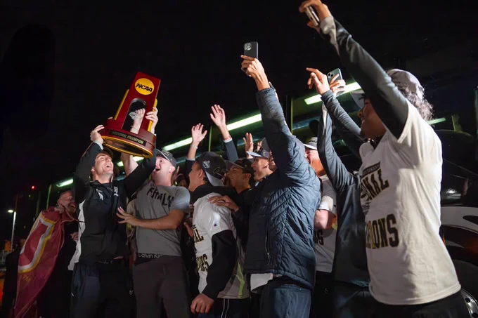 The MSU Texas Men's Soccer team celebrating after returning home from the championship game, holding up the national champion trophy and cheering. 