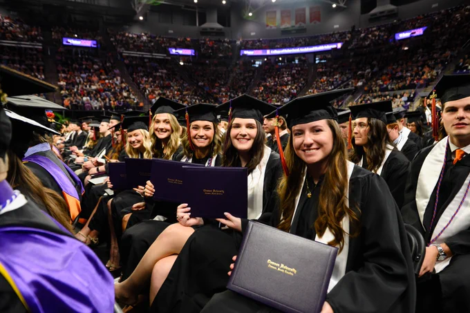 A group of students posing for a photo while seated at graduation.