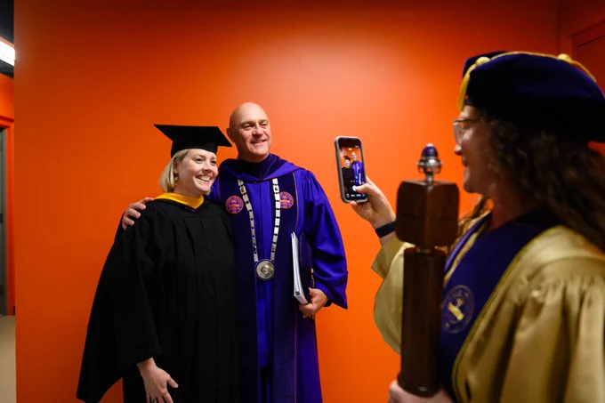 President Clements taking a photo with a student at graduation.