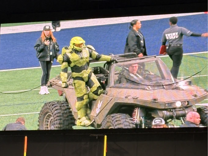 A photo of Master Chief hanging off the side of a Warthog at the Xbox Bowl