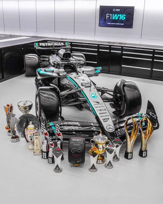 The W16 in the race bays in Brackley with the team's 2025 trophy haul positioned in front of the nose cone, in an arrow shape.