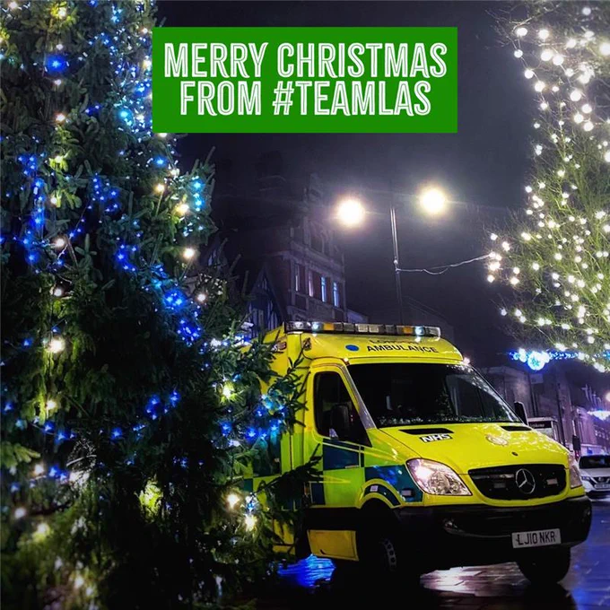 Ambulance in front of a Christmas tree with ' Merry Christmas from #TeamLAS on screen'