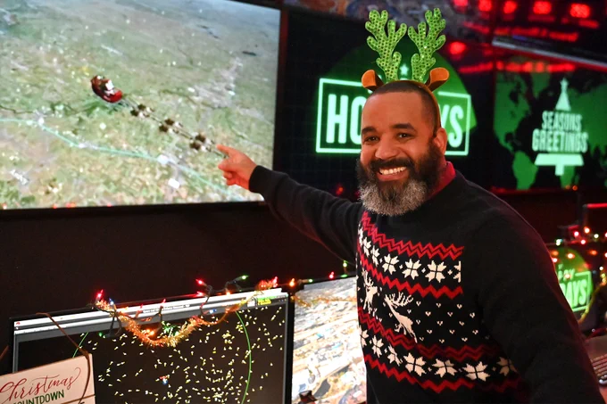 A man points at a television screen tracking Santa.