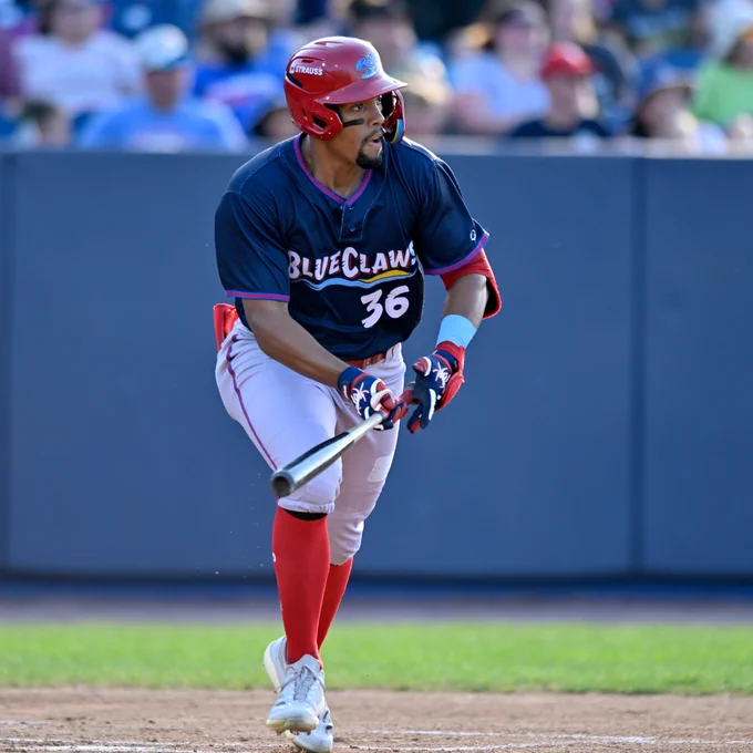 Avery Owusu-Asiedu runs out of the box in a navy BlueClaws jersey with grey pants