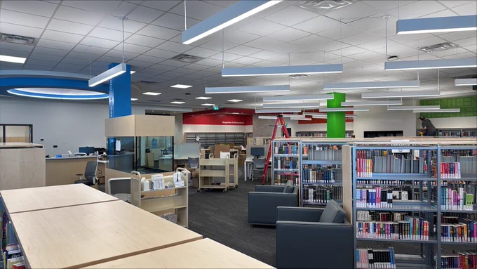 Interior of a modern library with colorful decor, featuring rows of books, seating areas, and a help desk.