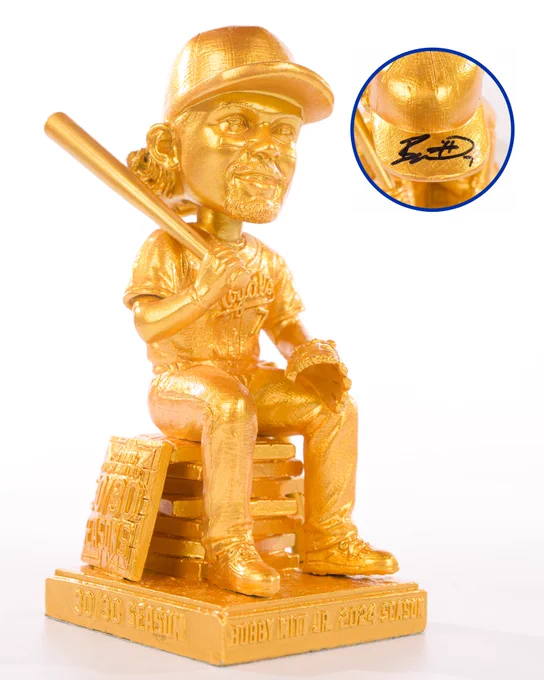 A photo of a golden Bobby Witt Jr. bobblehead set against a white background. A cutout photo shows a Bobby Witt Jr. signature on the bobblehead's hat.