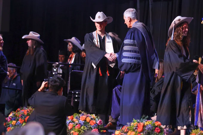 Former Mines Soccer player Marc Levin shakes hands with Mines President Paul Johnson at graduation as he earns his degree in Quantitative Biosciences and Engineering 