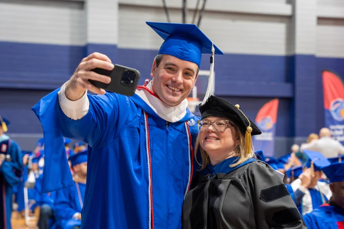 Graduate takes a selfie with a professor.