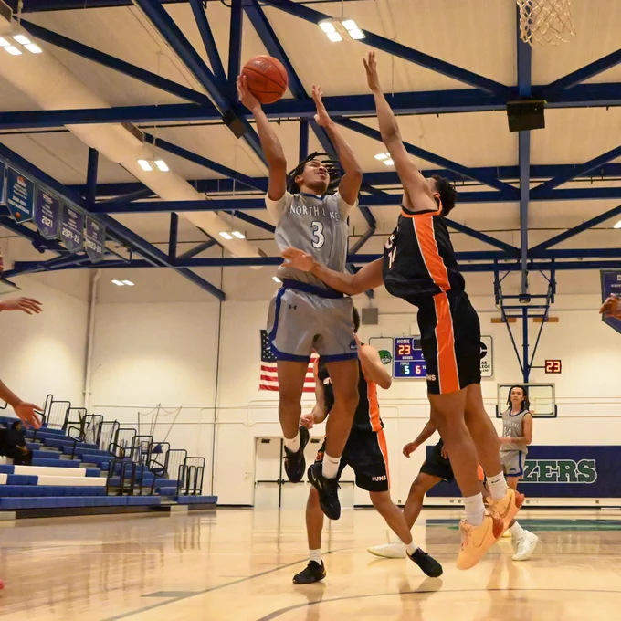 Dallas College North Lake men’s basketball’s Zaedyn Owens puts up a shot at the rim around a Dallas College Cedar Valley defender.