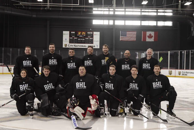 Team aces is wearing black jerseys and pose on the ice with the scoreboard and the Canadian and American flag behind them