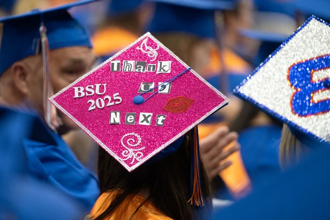 Boise State graduate hat with a design on it that says “Thank you next” in pink sparkles. 
