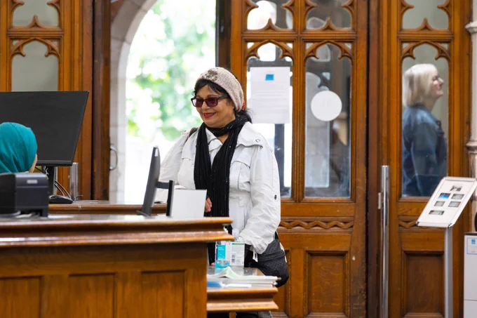 A customer smiles as she greets a female librarian. 