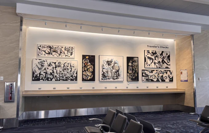 Paintings on display in a passenger waiting area at FLL.
Dominik Ambroise, “Traveler's Checks"
