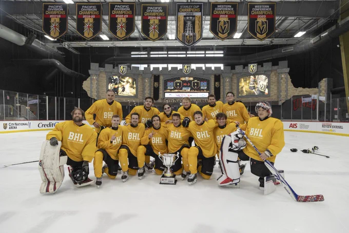 Team Mercurys, wearing yellow jerseys pose at centre ice in front of the city national Arena scoreboard with the Carnegie cup trophy placed in the middle of them