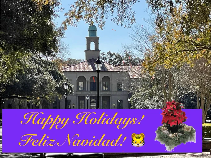 Outside, a building as a background, trees surrounding a message in English “happy holidays!” and Feliz Navidad in Spanish.