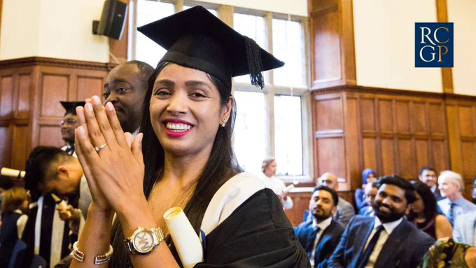 A photo of a woman at a graduation ceremony and she's smiling at the camera. 