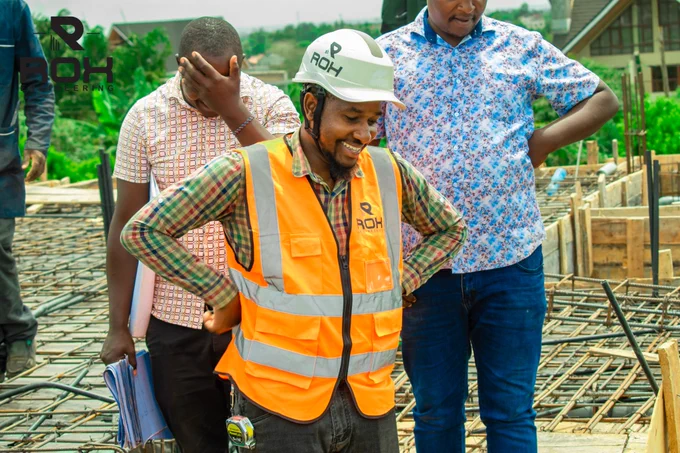 Eng. James Karori on a construction site, smiling and in high spirits while inspecting structural engineering works with the team.