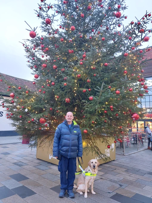 Alun and Mattie standing infront of a Christmas tree looking into the camera.