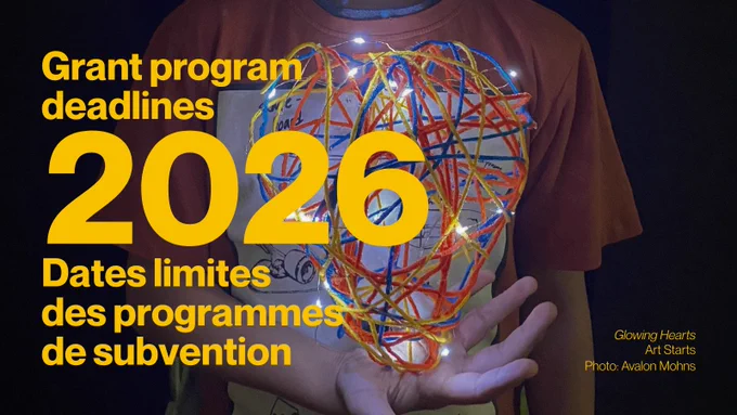 English: Child holding a glowing, colorful heart-shaped light. Text reads: “Grant program deadlines 2026.”
---
Français : Un enfant tenant un cœur lumineux coloré. Texte : « Dates limites des programmes de subvention 2026 ».