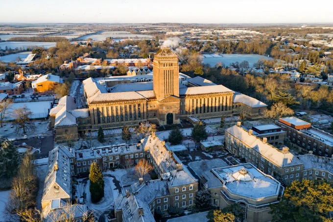 Aerial view of the Cambridge University Library and surrounding landscape dusted with snow, during sunrise.