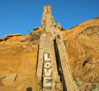 An old concrete tower built on a tawny sandstone bluff. At the base of the tower supports, someone has spray painted "LOVE".