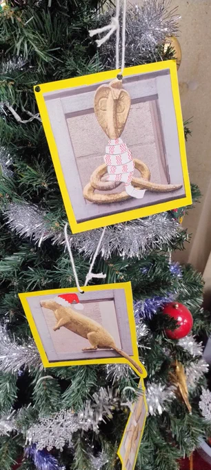 Snake and a rat decorations adorned with scarves and hats on a Christmas tree complete with tinsel and baubles.