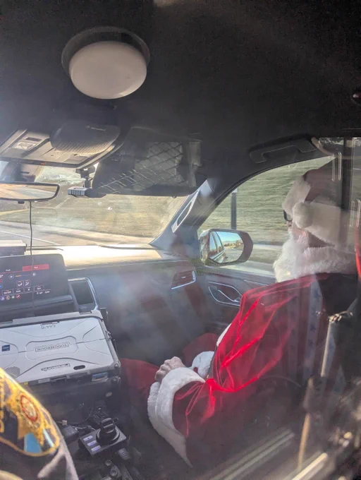 Santa riding in front seat of patrol car