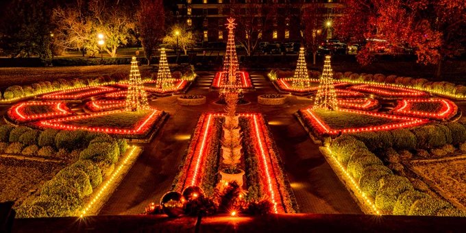 Nighttime view of the illuminated Christmas decorations with symmetrically arranged lights and topiary gardens.