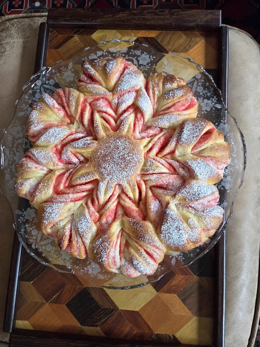 A star bread with pink filling inside and powdered sugar dusted all over it