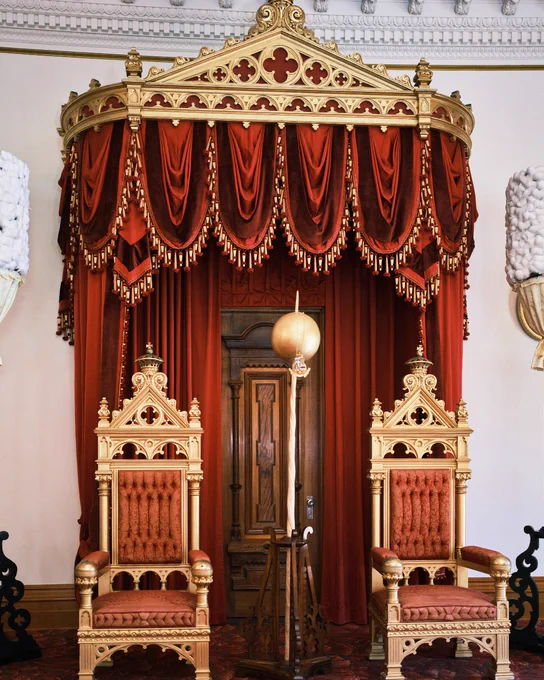Ornate red and gold thrones under a canopy in the Iolani Palace, Hawaii.