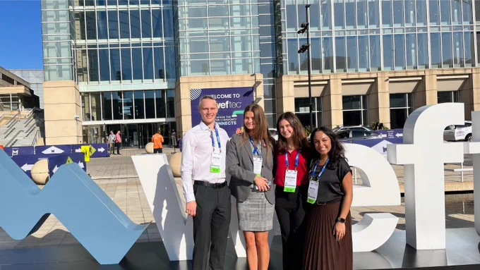 A student team smiles at the camera outside the convention center.