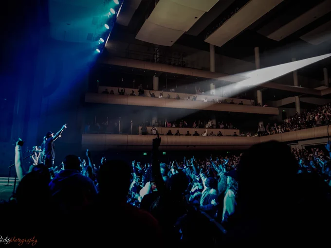 Concert at DeVos Performance Hall with a musician on stage reaching out to an enthusiastic audience under dramatic lighting.