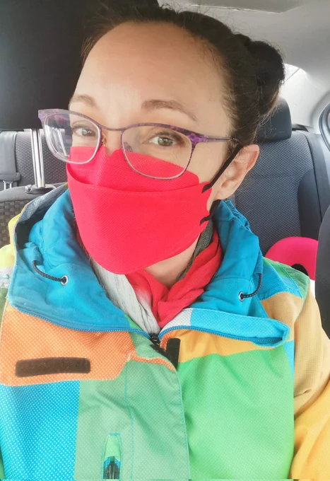 Brunette woman with glasses wearing a Kind KN95 mask in a car. 