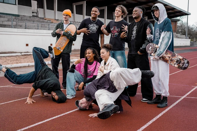 A group of young people from House of Wingz showcasing various poses and breakdancing on an athletics track in Blackpool. 