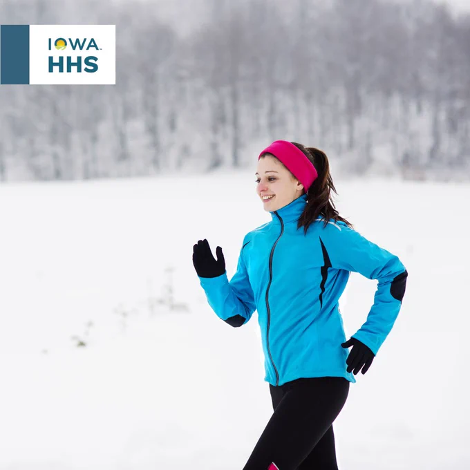 Person jogging in the snow wearing a blue jacket and a pink headband, with the Iowa HHS logo in the upper left corner.