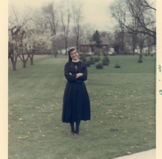 Blurry photo from 1967 of Sister Helen Prejean wearing a Catholic nun’s habit, standing outside, with trees and a house in the distant background.