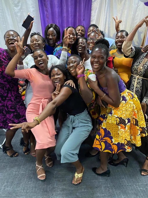 Group of joyful people posing together at a social gathering, smiling and making playful gestures towards the camera.