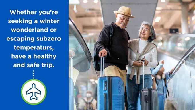An older couple walks through an airport terminal pulling rolling suitcases and smiling at each other. Other travelers are visible in the background. On the left, a blue panel reads, “Whether you’re seeking a winter wonderland or escaping subzero temperatures, have a healthy and safe trip,” with an airplane icon below.