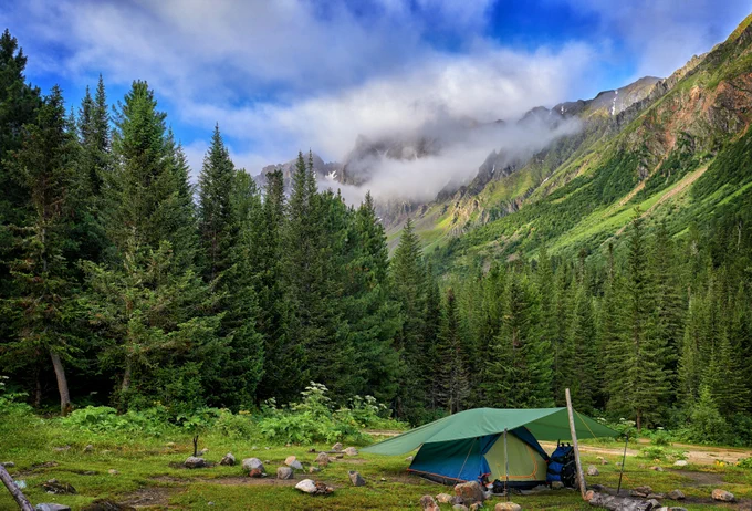 A scenic photo of a tent with mountains in the background. 