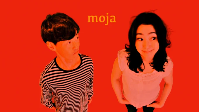 Photo of the two members of Moja standing next to each other, one with a striped shirt, the other with a white shirt. On top of the photo they have put a red filter.