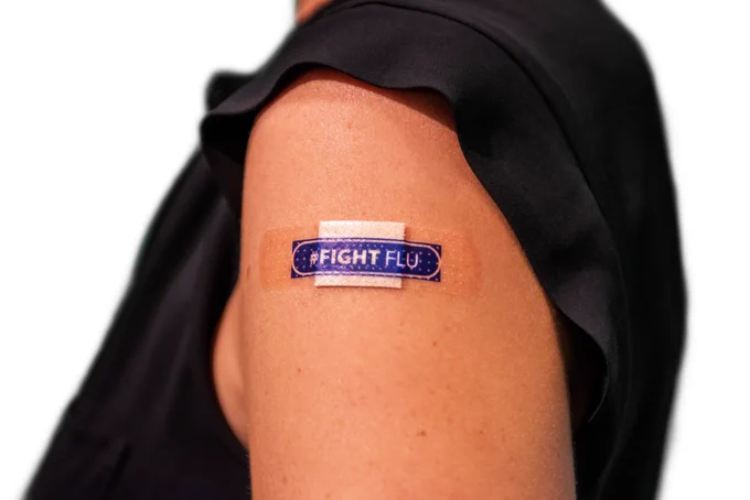 Image of a female in a black shirt and her upper arm has a #Fight Flu blue bandage. 