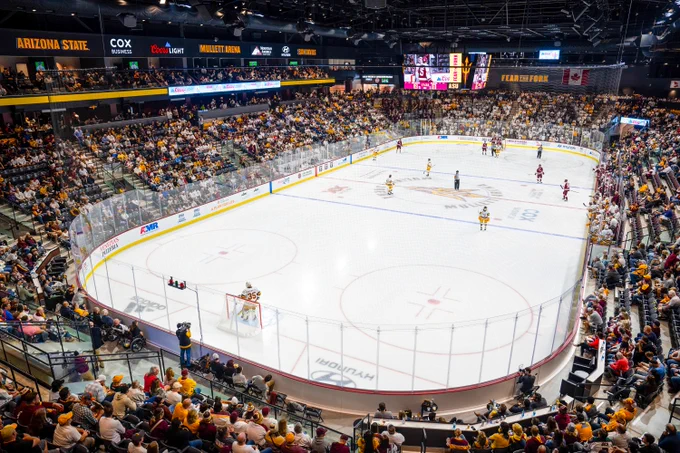 Wide view of a packed indoor ASU ice hockey arena with players on the ice and fans filling the stands.
