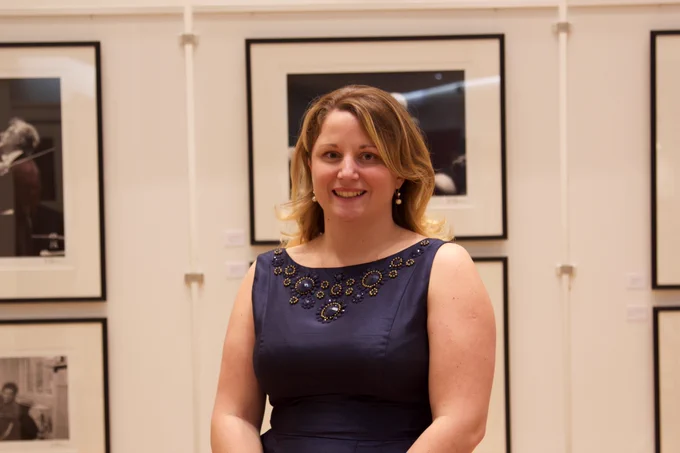 Photo of Sophie smiling at the camera. She has a blonde bob haircut and is wearing a black dress.