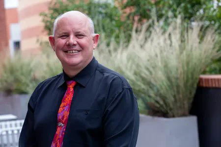 A photograph of Professor Scott Bowman in a black shirt and a red patterned tie.