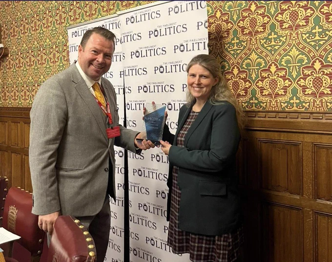 Rachael Maskell being handed a plaque by a gentleman in a room in the parliamentary estate.